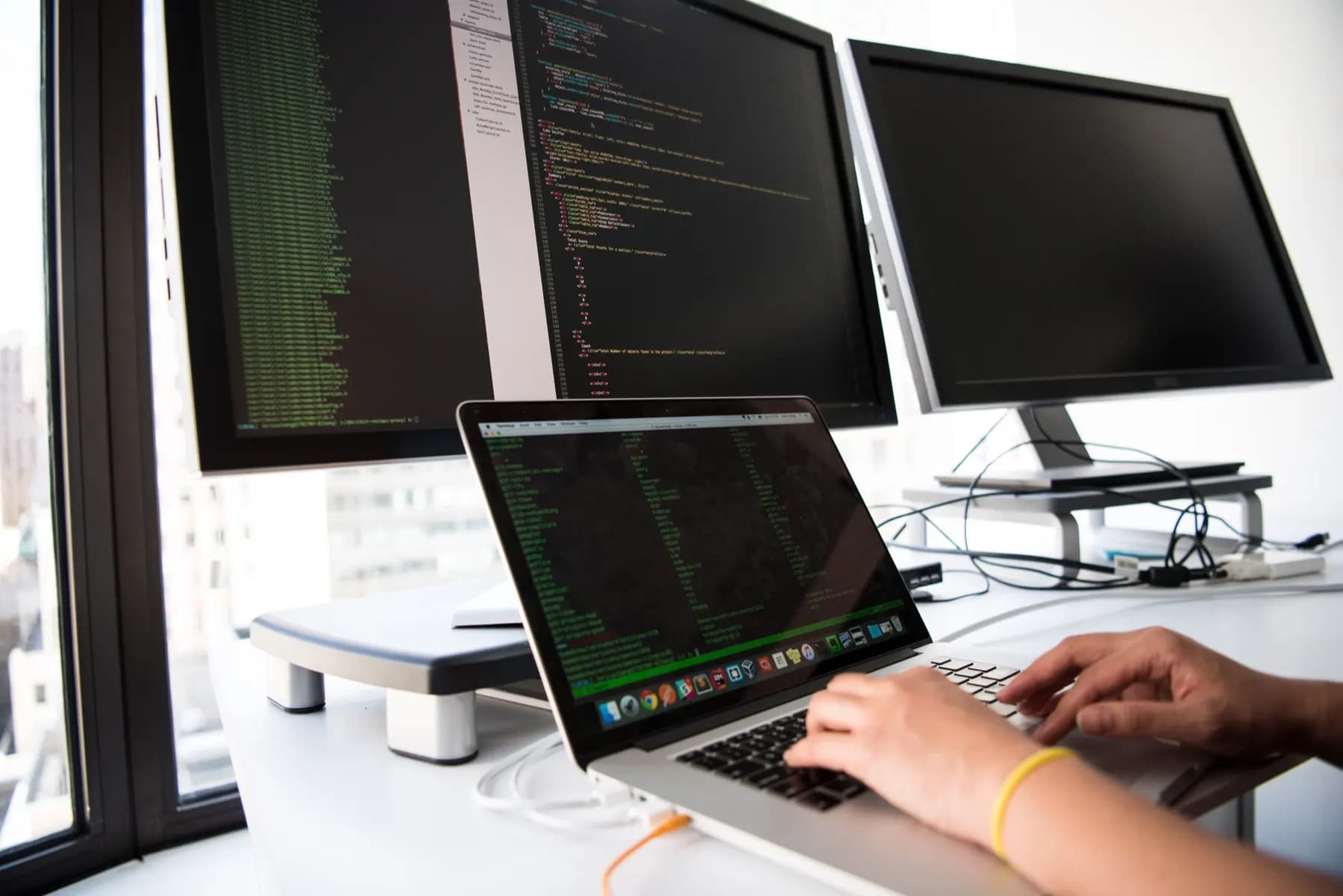 Programador escribiendo código frente a varios monitores