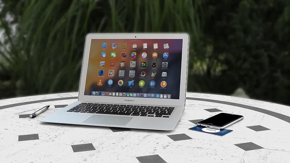Laptop y teléfono sobre una mesa al aire libre